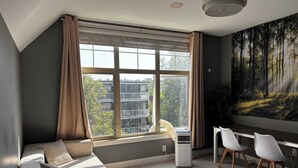 A modern bedroom with a large window, a bed, a desk, and a chair. - Grizzly - Private Luxury Unit near DT and 17th Av (Calgary)