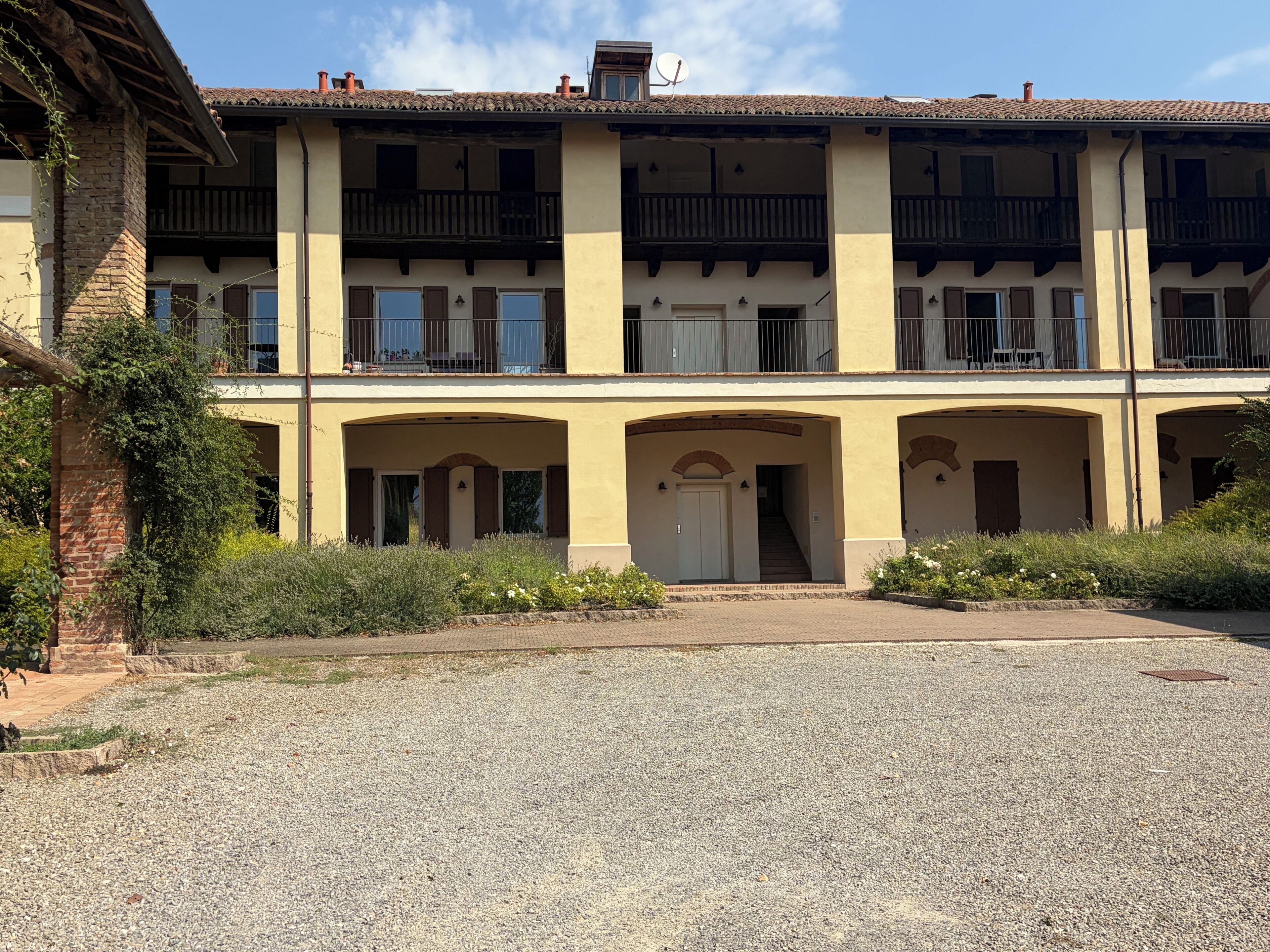 A multi-story building with a central courtyard, balconies, and a gravel driveway.