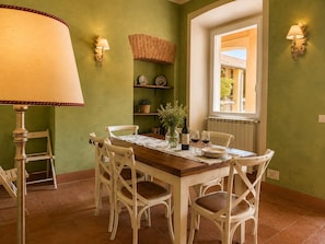 A dining area with a wooden table, white chairs, a lamp, and a window with a view.
