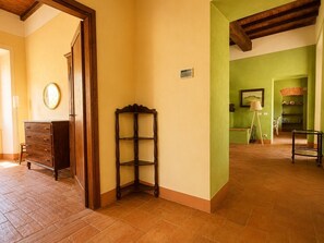 A room with a wooden dresser, a corner table, and a green wall with a painting.