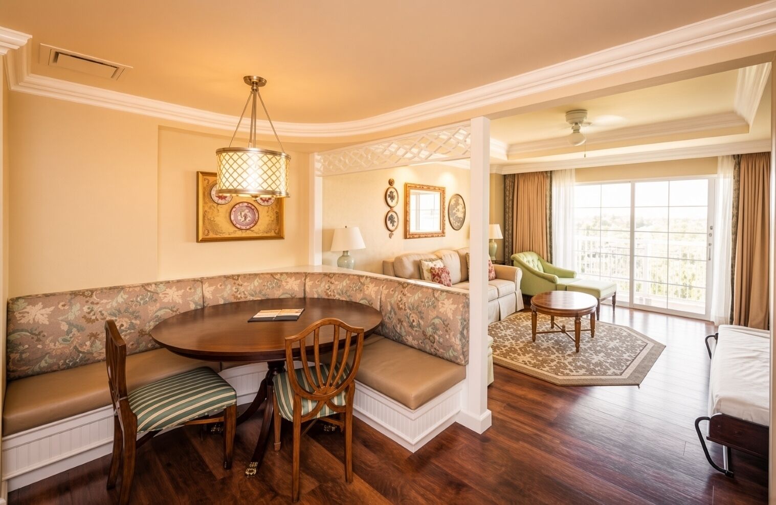 A room with a round dining table, a sofa, and a green armchair.