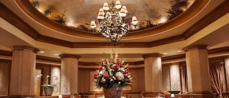 Comedor formal con candelabro, centro de mesa floral y decoración clásica.