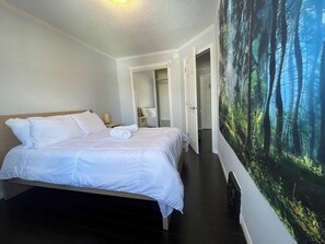 Ein Schlafzimmer mit einem Bett, einem Nachttisch, einer Wandlampe und einer Waldfresco.