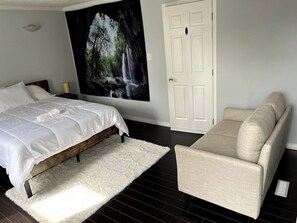 A bedroom with a bed, a white rug, a sofa, and a large wall mural. - Bear - Private Master Bedroom near DT and 17th Av (Calgary)