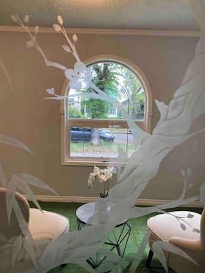 Ein Zimmer mit einem großen Bogenfenster, einer weißen abstrakten Skulptur und zwei Stühlen.