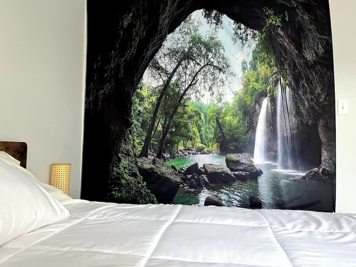 Un lit offrant une vue sur une cascade, visible à travers une structure ressemblant à une grotte.