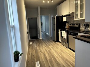A kitchen with a central island, stainless steel appliances, and a wooden floor. - Wolf - Private Bedroom near Downtown and 17th Av (Calgary)