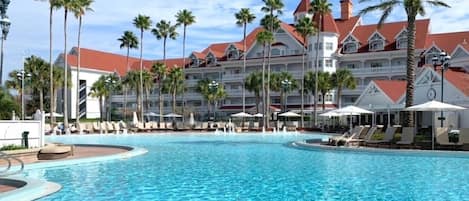 Un hotel con una piscina grande rodeada de palmeras y sillas de descanso.