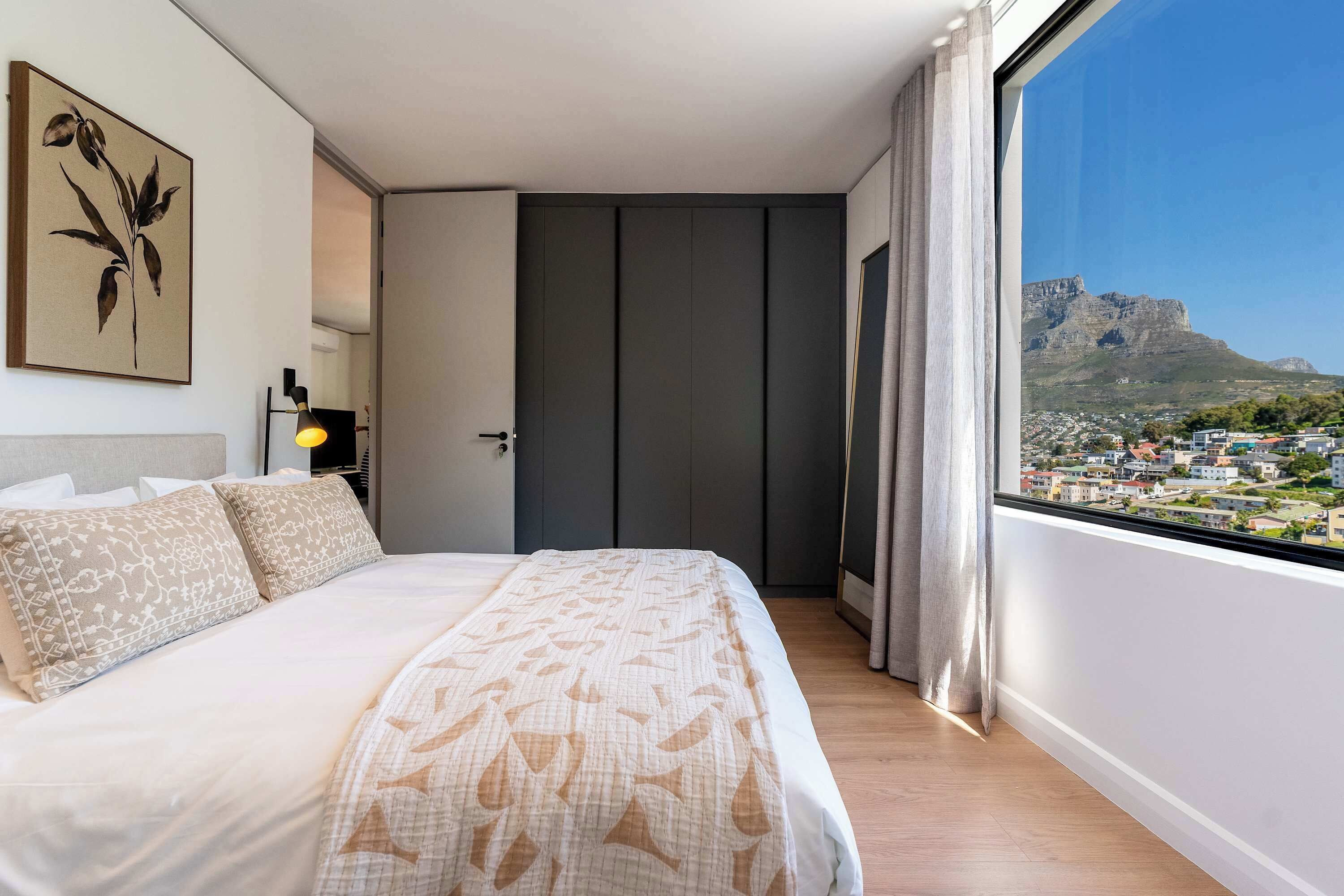 Ein Schlafzimmer mit Bett, einer Tür, einem Fenster und Blick auf einen Berg.