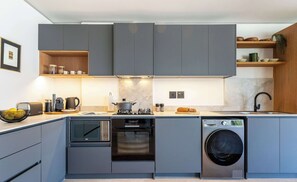 Eine moderne Küche mit grauen Schränken, einem Backofen, einer Mikrowelle und einem Geschirrspüler.