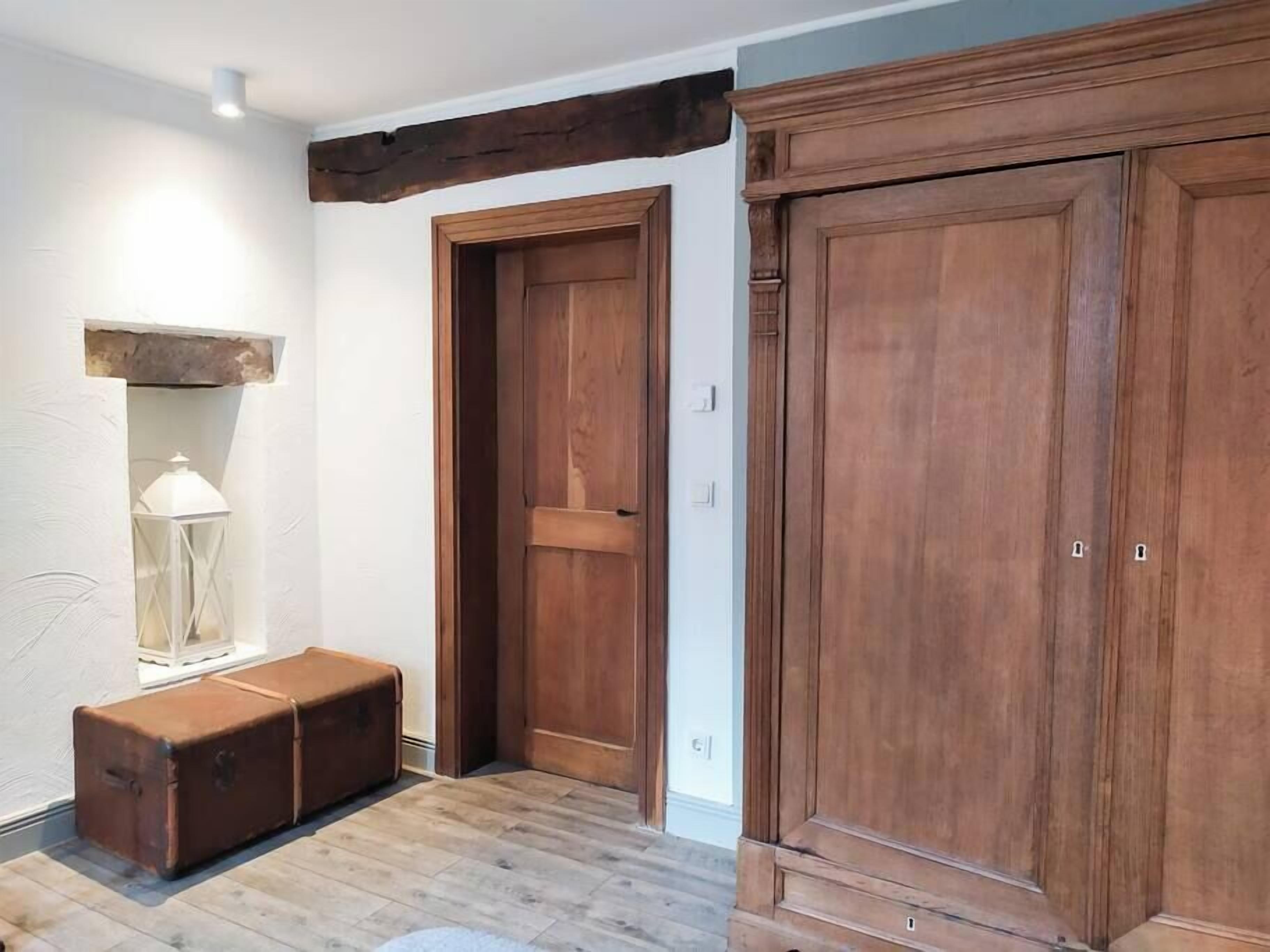 Un couloir avec des portes en bois et un banc.