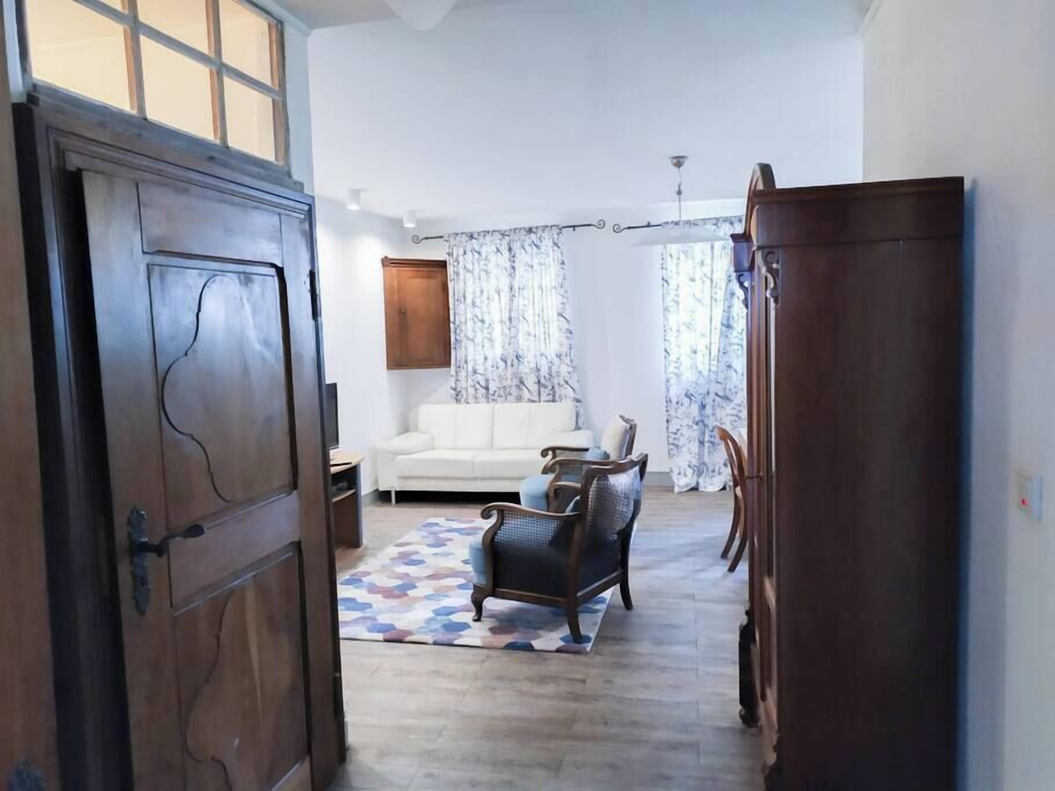 Une pièce avec un canapé blanc, un tapis à motifs et un meuble en bois.