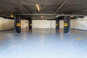 Un vaste parking souterrain doté de piliers en béton et de murs blancs.