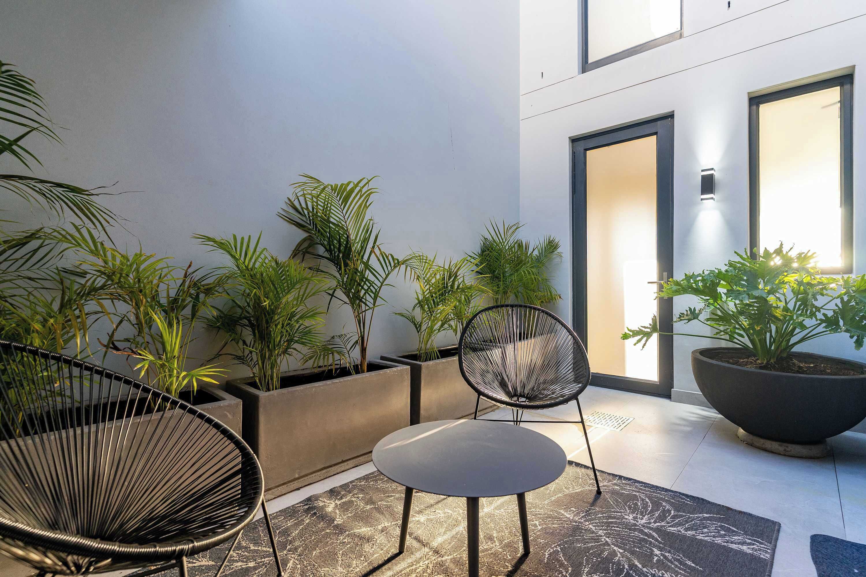 Een moderne buiten zithoek met twee stoelen, potplanten en een grote plantenbak.