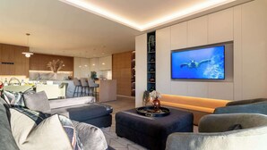 Uma sala de estar moderna com uma grande televisão de tela plana, um sofá e uma mesa de centro.