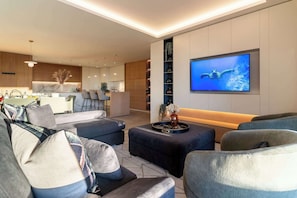 Ein modernes Wohnzimmer mit einem großen Flachbildfernseher, einer Couch und einem Couchtisch.
