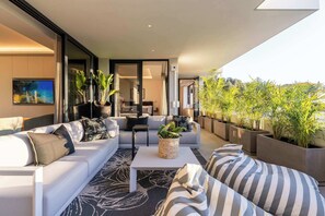 A modern living room with a sofa, a coffee table, and potted plants. - Walk to beach, Pool, Camps Bay -Terrace Royale Apt (Cape Town)