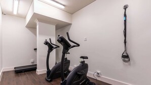 A room with two stationary bikes, a mirror, and a wall-mounted exercise equipment. - City Views, Shared Gym, Cape Town -York Cityscape Apt (Cape Town)