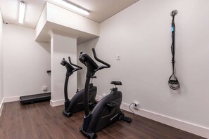 A room with two stationary bikes, a mirror, and a wall-mounted exercise equipment. - City Views, Shared Gym, Cape Town -York Cityscape Apt (Cape Town)