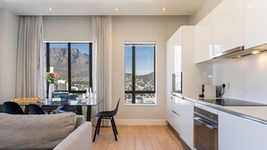 Uma cozinha moderna com vista para a cidade, uma área de jantar com mesa e cadeiras, e um sofá.