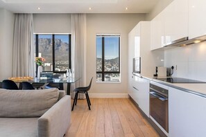 Eine moderne Küche mit Blick auf eine Stadtlandschaft, ein Essbereich mit Tisch und Stühlen sowie eine Couch.