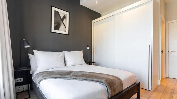 Quarto com cama, mesas de cabeceira, guarda-roupa e um quadro na parede.