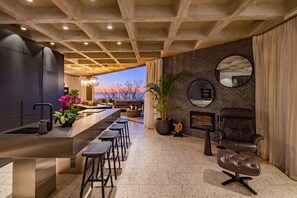 Eine moderne Küche mit Bar, Kamin und Blick auf den Sonnenuntergang.