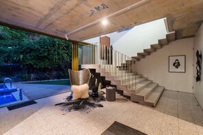 Ein modernes Interieur mit Treppe, einem Sessel und einer kleinen Außenanlage mit Pool.