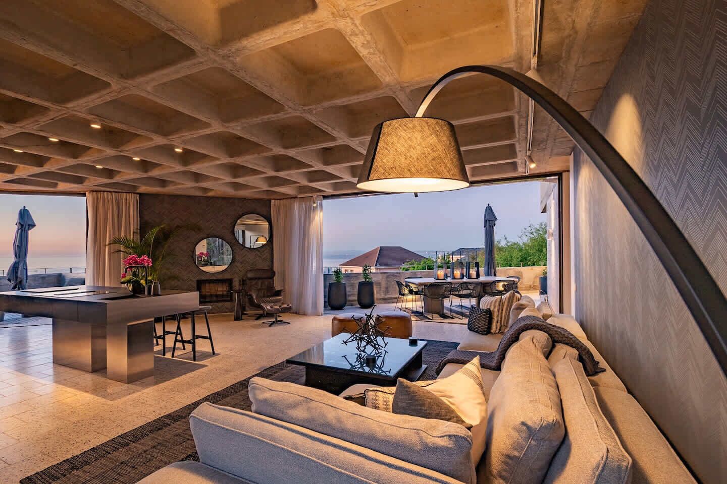 Een ruime woonkamer met een modern design, met een bank, een salontafel en een zithoek buiten.