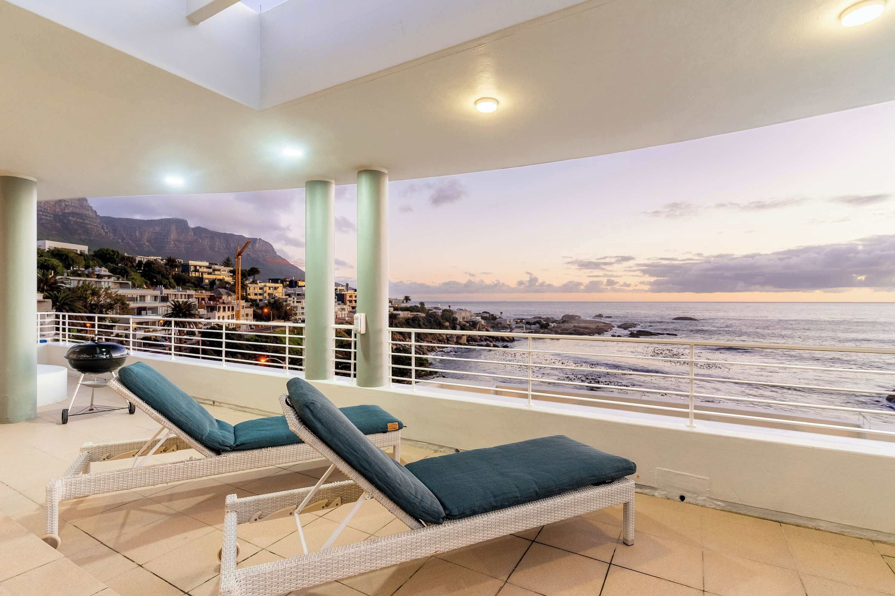 Ein Balkon mit Korbsitzmöbeln und Blick auf den Ozean.
