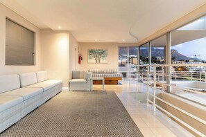 A modern living room with a sofa, armchair, and a painting on the wall. - Sunset Azure Penthouse - Panoramic Views, PVT Pool (Cape Town)
