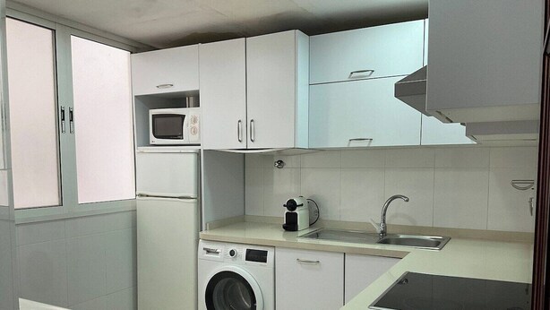 A compact kitchen with a washing machine, microwave, and sink. - AVE station at 10 min walking - Sostoa Apartment (Málaga)