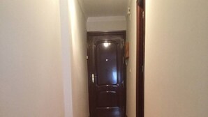 A narrow hallway with wooden flooring and a dark door at the end. - AVE station at 10 min walking - Sostoa Apartment (Málaga)