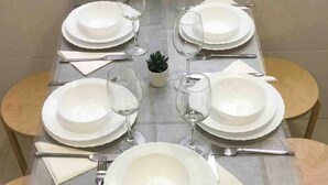 A dining table set for six with white plates, cutlery, and glasses, surrounded by wooden chairs. - AVE station at 10 min walking - Sostoa Apartment (Málaga)