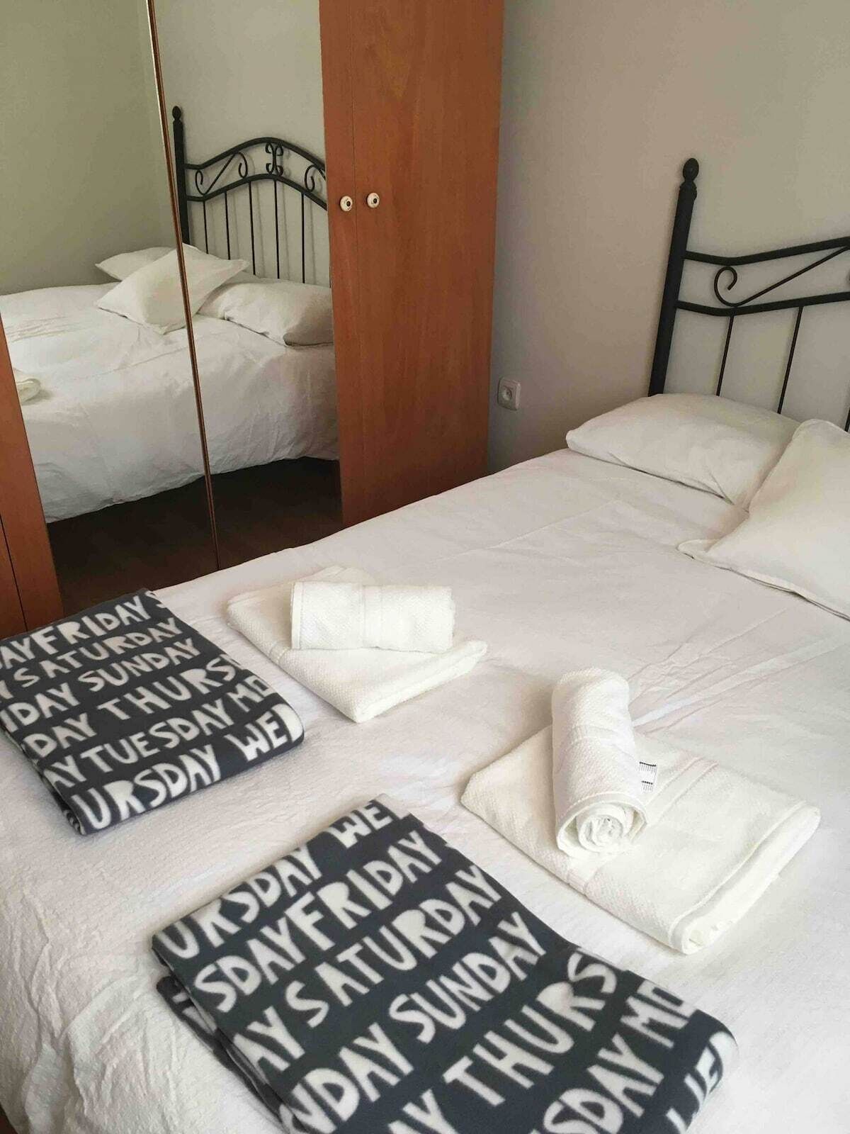 Una cama bien hecha con una toalla doblada y otra toalla estampada con texto.
