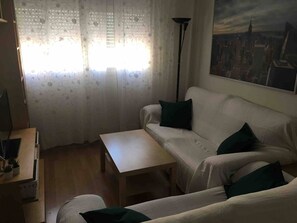 Ein Wohnzimmer mit Sofa, Couchtisch, Lampe und einem Stadtbild an der Wand.