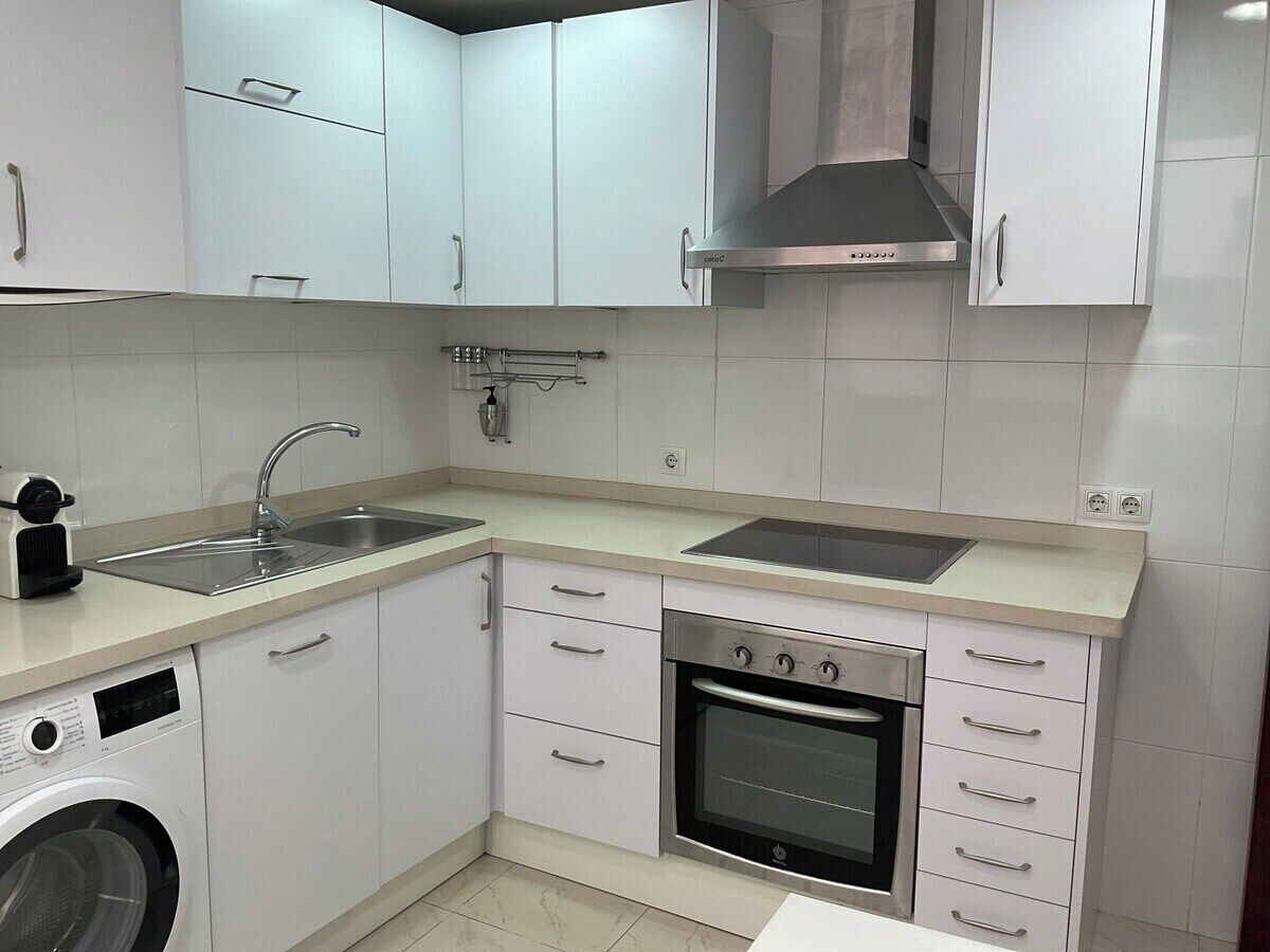 A compact kitchen with a built-in washing machine, a stove, and a sink.
