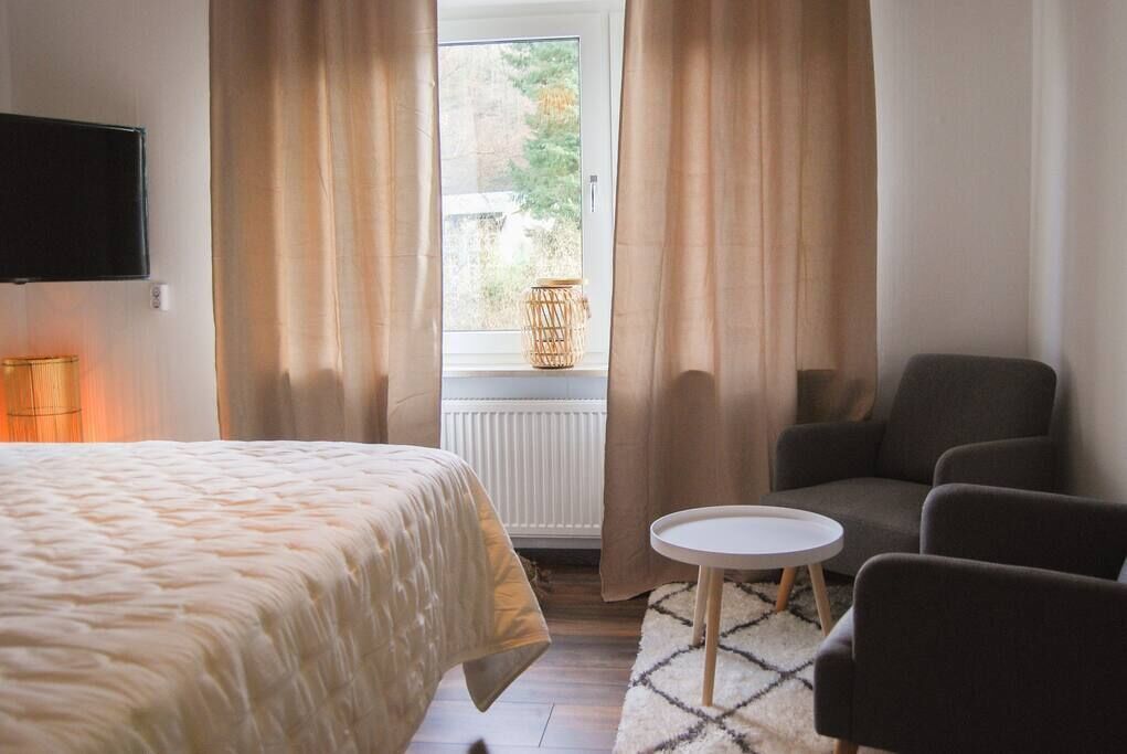 Ein Hotelzimmer mit einem Bett, einer Sitzecke mit Tisch und einem fenster mit Vorhängen.