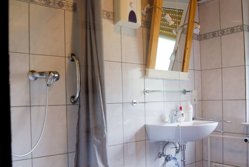Ein Badezimmer mit Dusche, Waschbecken und Spiegel.