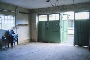 Ett rum med betongväggar, ett fönster, en grön grind och en stol.