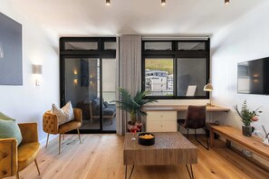 Ein modernes Wohnzimmer mit Couch, Schreibtisch, Fernseher und Couchtisch.