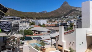 A residential area with a prominent mountain in the background, modern buildings, and a rooftop pool. - Views, BBQ, Balcony, Sea Point - Jade Views Studio (Cape Town)
