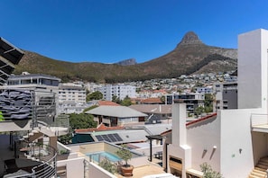 Ein Wohngebiet mit einem markanten Berg im Hintergrund, modernen Gebäuden und einem Pool auf dem Dach.