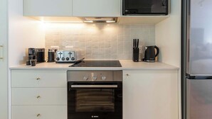 A modern kitchen with white cabinets, a Bosch oven, a microwave, and a stainless steel refrigerator. - Views, BBQ, Balcony, Sea Point - Jade Views Studio (Cape Town)