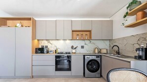 A modern kitchen with built-in appliances, a marble backsplash, and wooden shelves. - Stunning Views, Duplex, Bo-Kaap - Aerie Penthouse (Cape Town)
