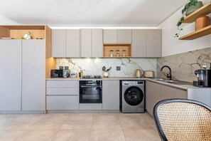 A modern kitchen with built-in appliances, a marble backsplash, and wooden shelves. - Stunning Views, Duplex, Bo-Kaap - Aerie Penthouse (Cape Town)