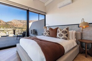A modern bedroom with a large bed, a view of the city, and a balcony. - Stunning Views, Duplex, Bo-Kaap - Aerie Penthouse (Cape Town)