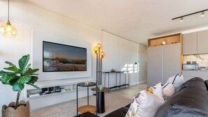 A modern living room with a flat-screen TV, a large potted plant, a leather sofa, and a minimalist coffee table. - Stunning Views, Duplex, Bo-Kaap - Aerie Penthouse (Cape Town)