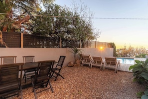 Eine Terrasse mit Tisch und Stühlen, ein Pool und eine Umzäunung.