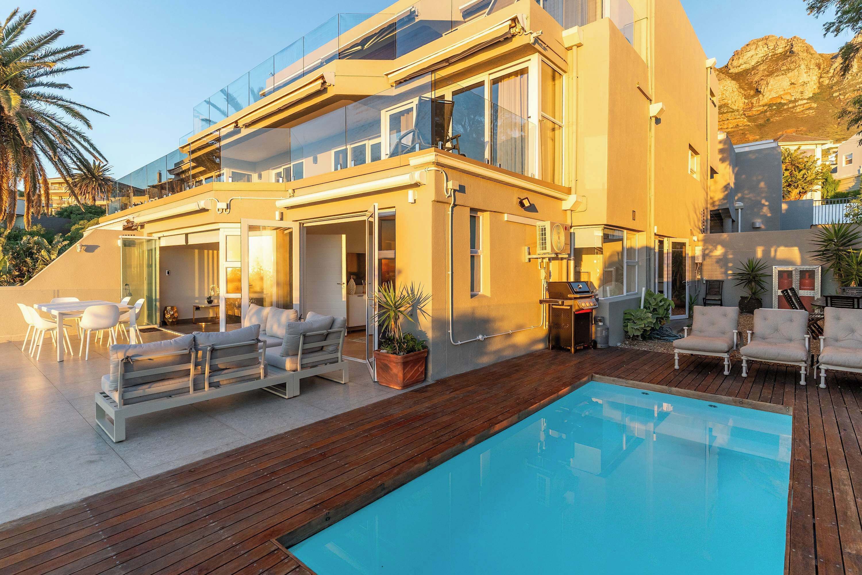 A modern house with a pool, outdoor seating, and a mountain backdrop.